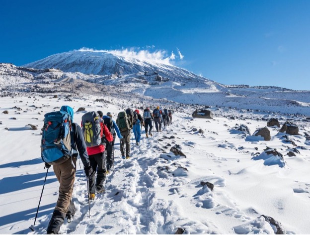 Kilimanjaro guide leading climbers at a slow pace on a steep slope.
