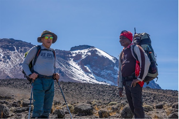 Climber taking a short break while trekking uphill on Kilimanjaro.