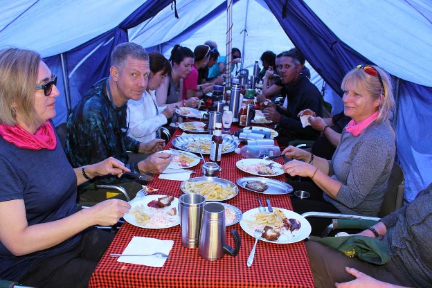Trekkers eating a high-energy meal during a Kilimanjaro climb.