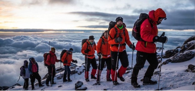 Climber using trekking poles while ascending Kilimanjaro slope.